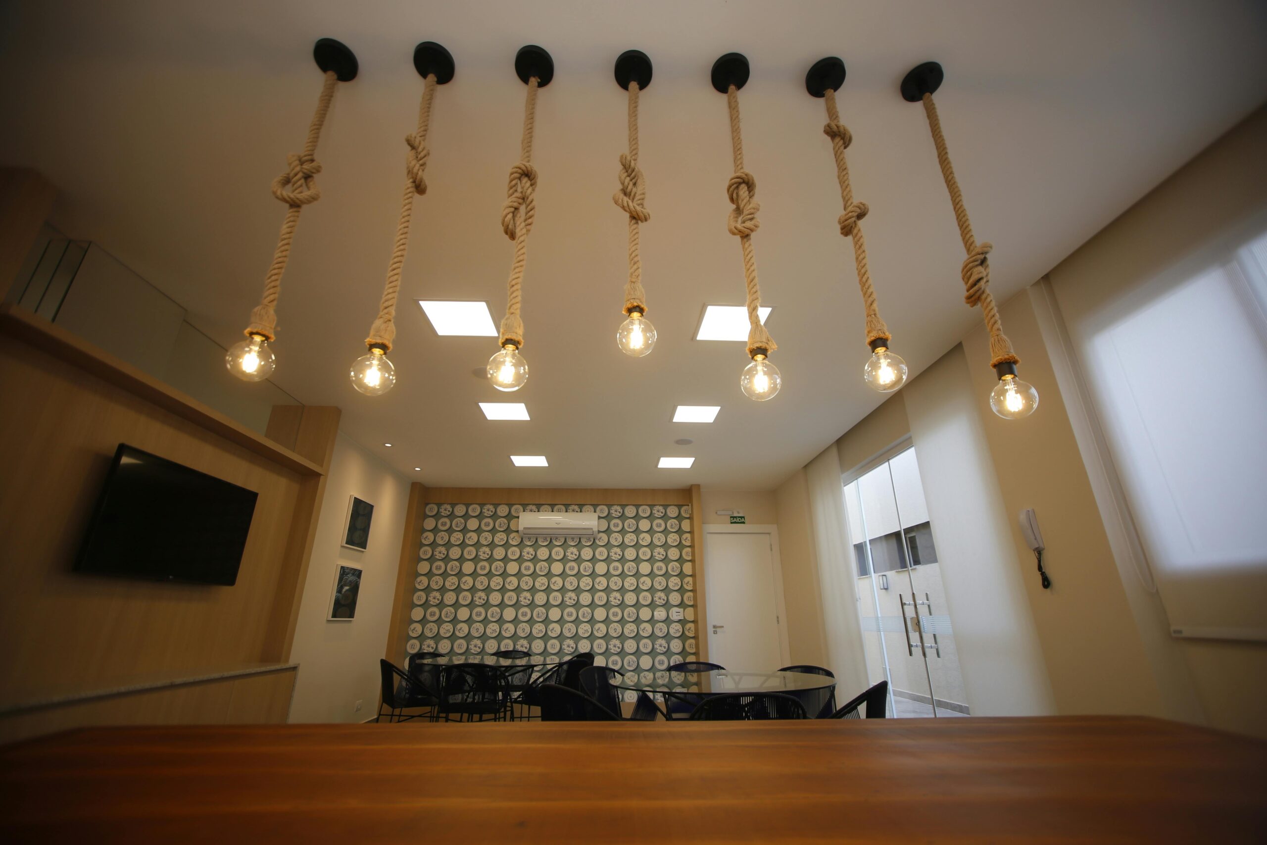 Home Stylish room interior featuring rope-hung light bulbs and geometric wall design.